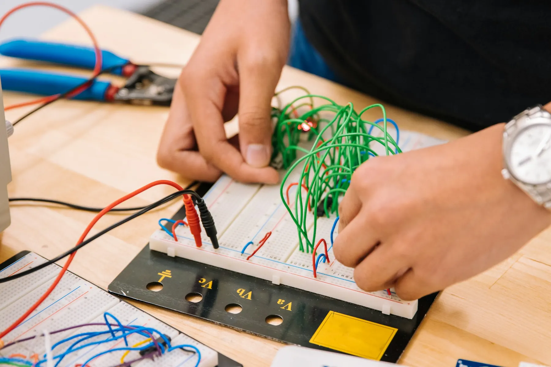 Hands wiring a breadboard and microcontroller with jumper wires