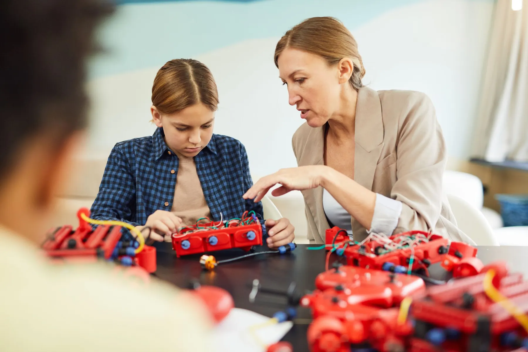 A teacher closely supervising students working with electronics
